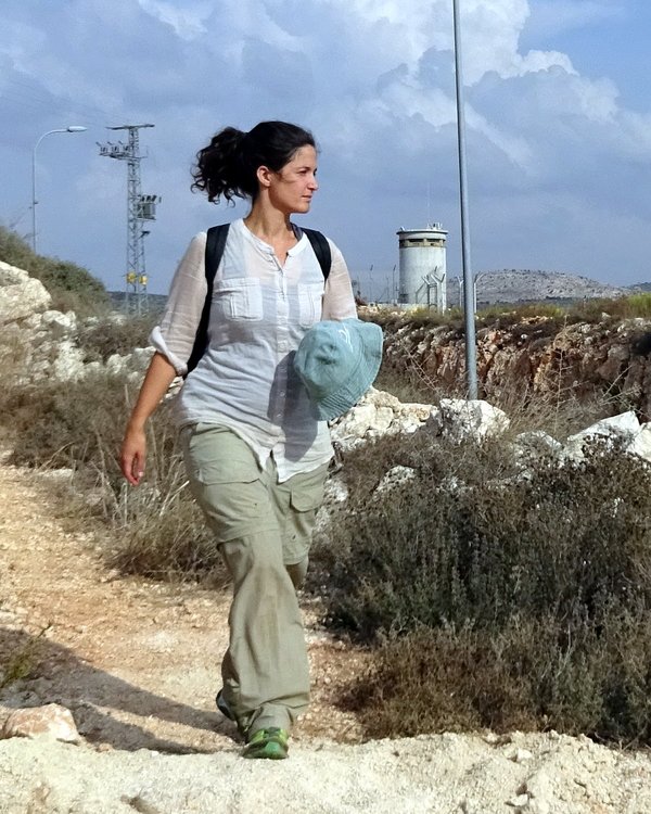 woman walking with miltary watch tower behind